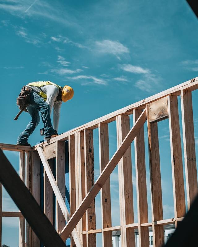Un carpintero trabajando en la estructura de una casa contra un cielo azul